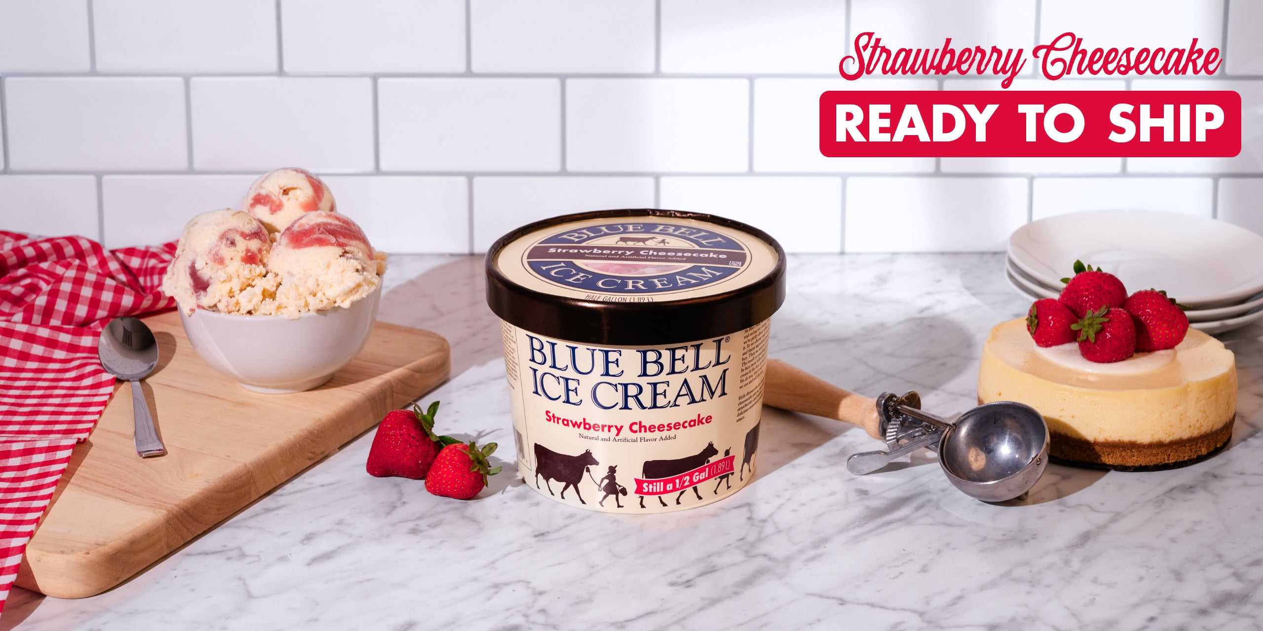 Blue Bell Strawberry Cheesecake Ice Cream now Ready to Ship with a picture of an ice cream carton, strawberries, ice cream, cheesecake, dipper and bowls in a kitchen setting.