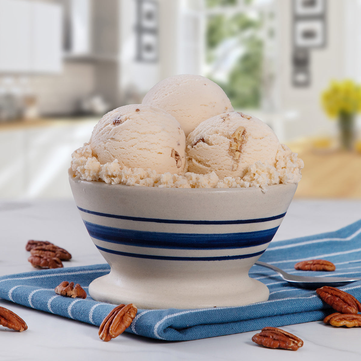 Blue Bell Buttered Pecan Ice Cream in a bowl with pecans placed on a blue towel