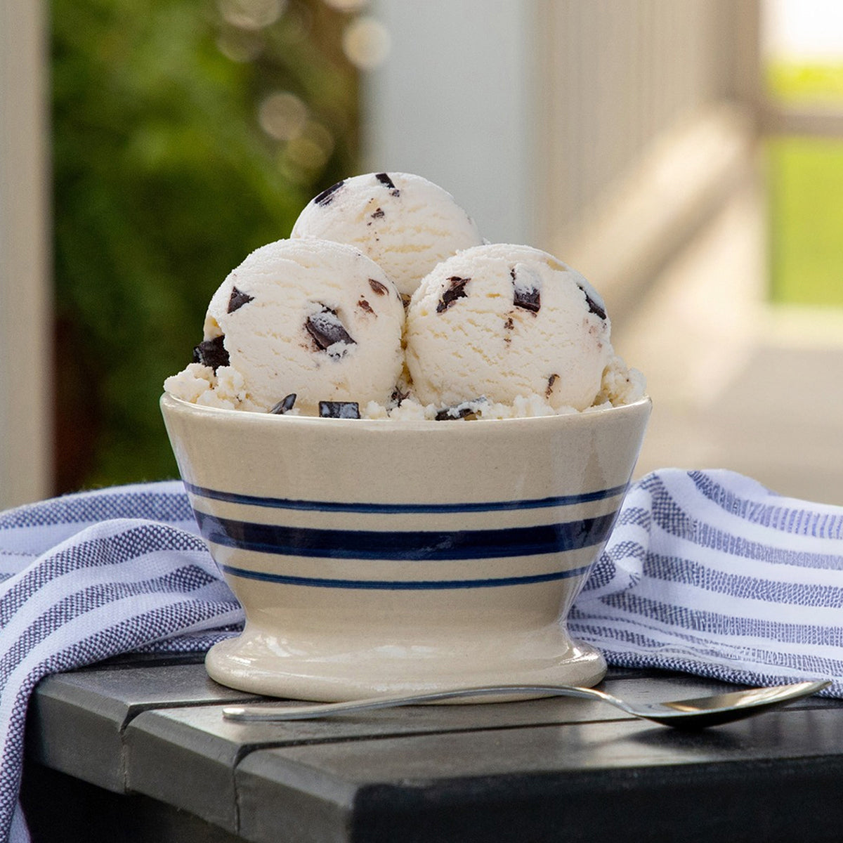 Bowl of Blue Bell Chocolate Chip Ice Cream with a spoon next to a blue and white towl