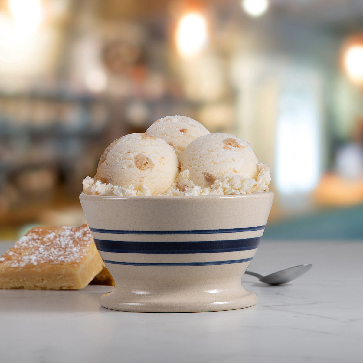 Bowl of Blue Bell Gooey Butter Cake Ice Cream with a gooey butter cake bar in spoon in a bright kitchen setting