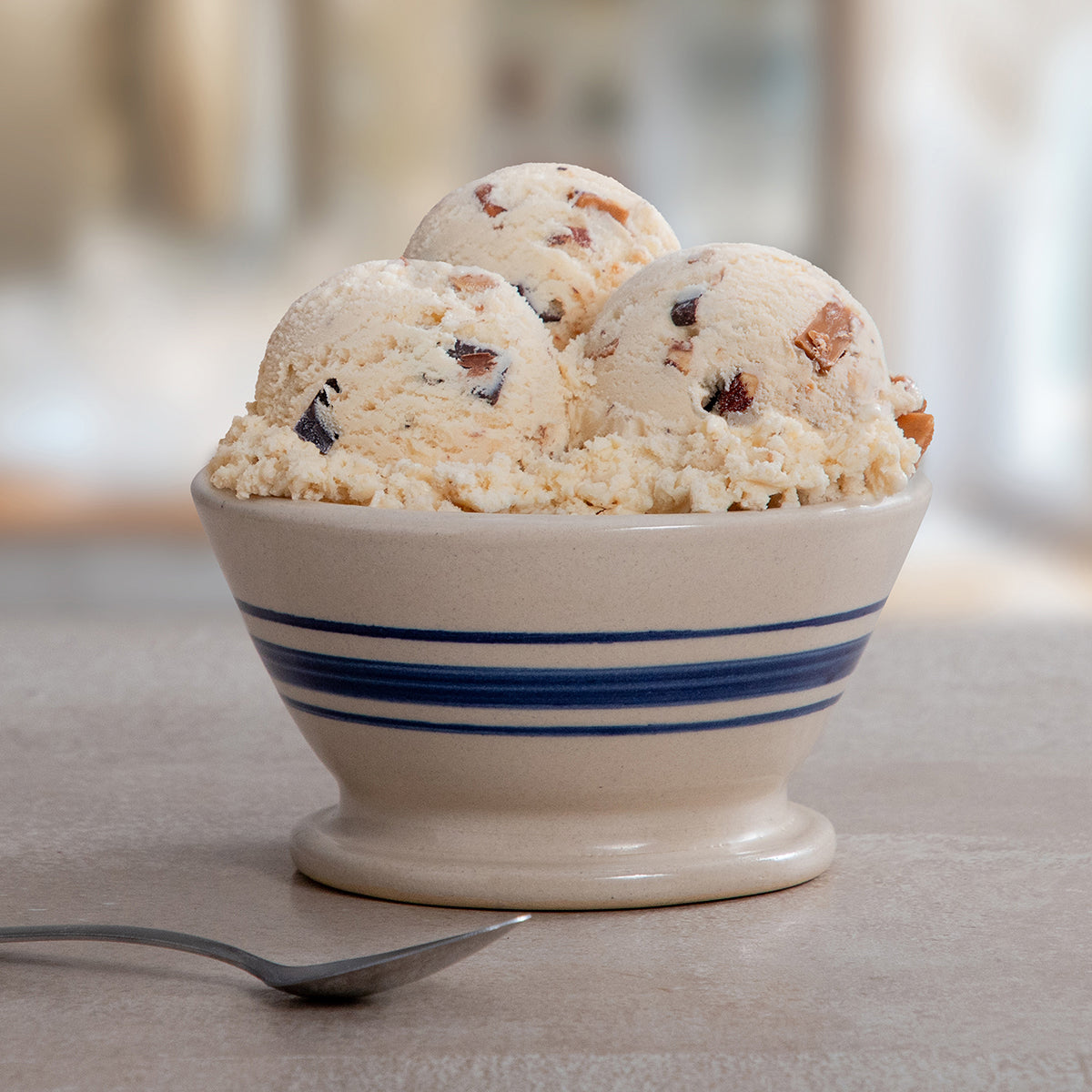Bowl of Blue Bell Moo-llennium Crunch Ice Cream with a spoon on a marble table