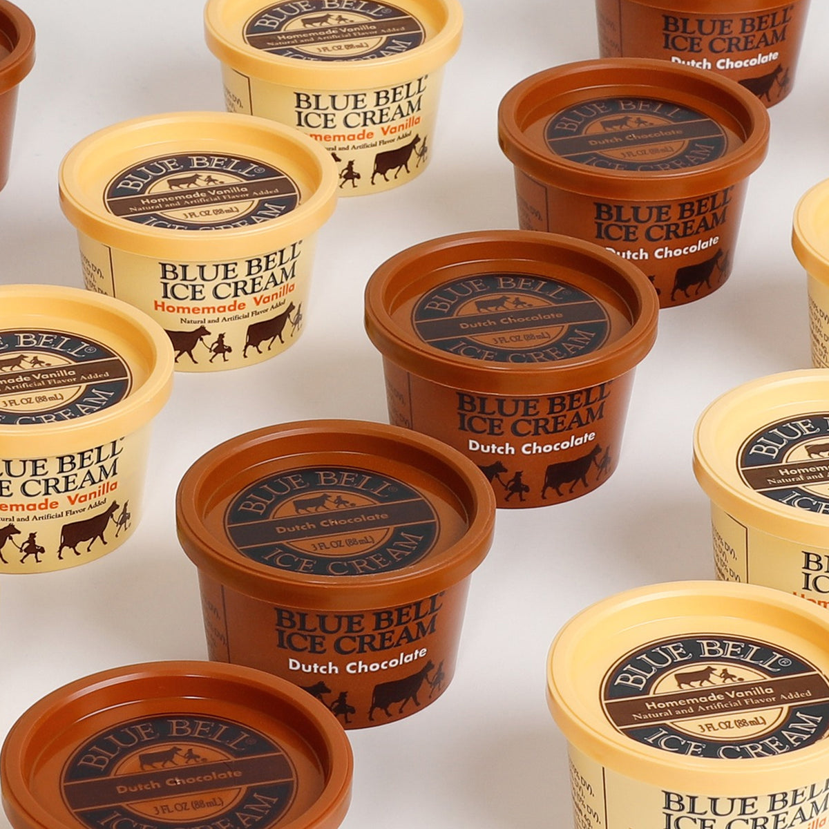 Multiple Blue Bell Ice Cream cup containers arranged on a white background, showing different flavors including Dutch Chocolate and Homemade Vanilla.