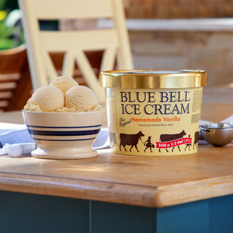 Blue Bell Homemade Vanilla Ice Cream container with vanilla ice cream in a bowl on a wooden table.