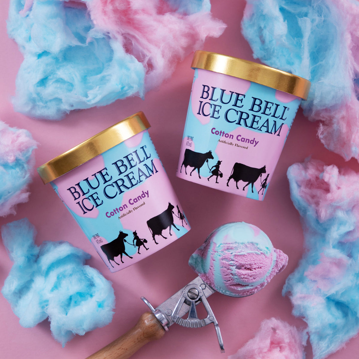 Two Blue Bell Ice Cream pints of Cotton Candy flavor with gold lids, arranged on a pink background with cotton candy and a scoop of pink and blue ice cream.